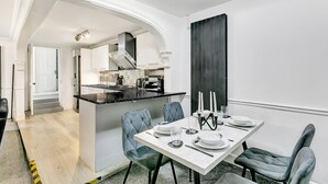 A modern kitchen with a central island, white cabinetry, and a dining area with a table set for four.