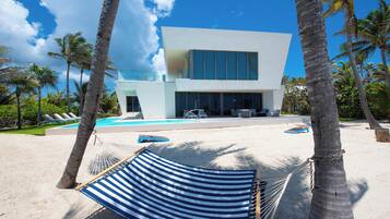 Un bâtiment moderne doté d’une piscine, entouré de palmiers et agrémenté d’un hamac.