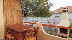 Una mesa y sillas de madera en un balcón con valla blanca y plantas en macetas.