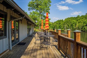 A wooden deck with outdoor seating and a view of a lake. - Mountain Dazzzze - HOT TUB - Pets Ok - Hike - Fish - Sleeps 8 (Watauga County)