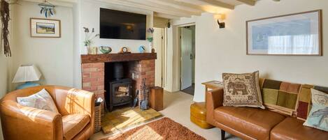 A cozy living room with a fireplace, leather sofas, and a television.
