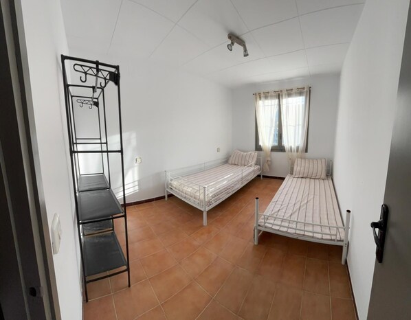 A dormitory room with two single beds, a metal wardrobe, and a tiled floor. - Casita moderna vacacional en roses (roses)