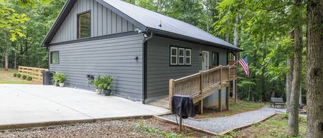 A cabin with a covered porch, a flag, and a wooden deck.