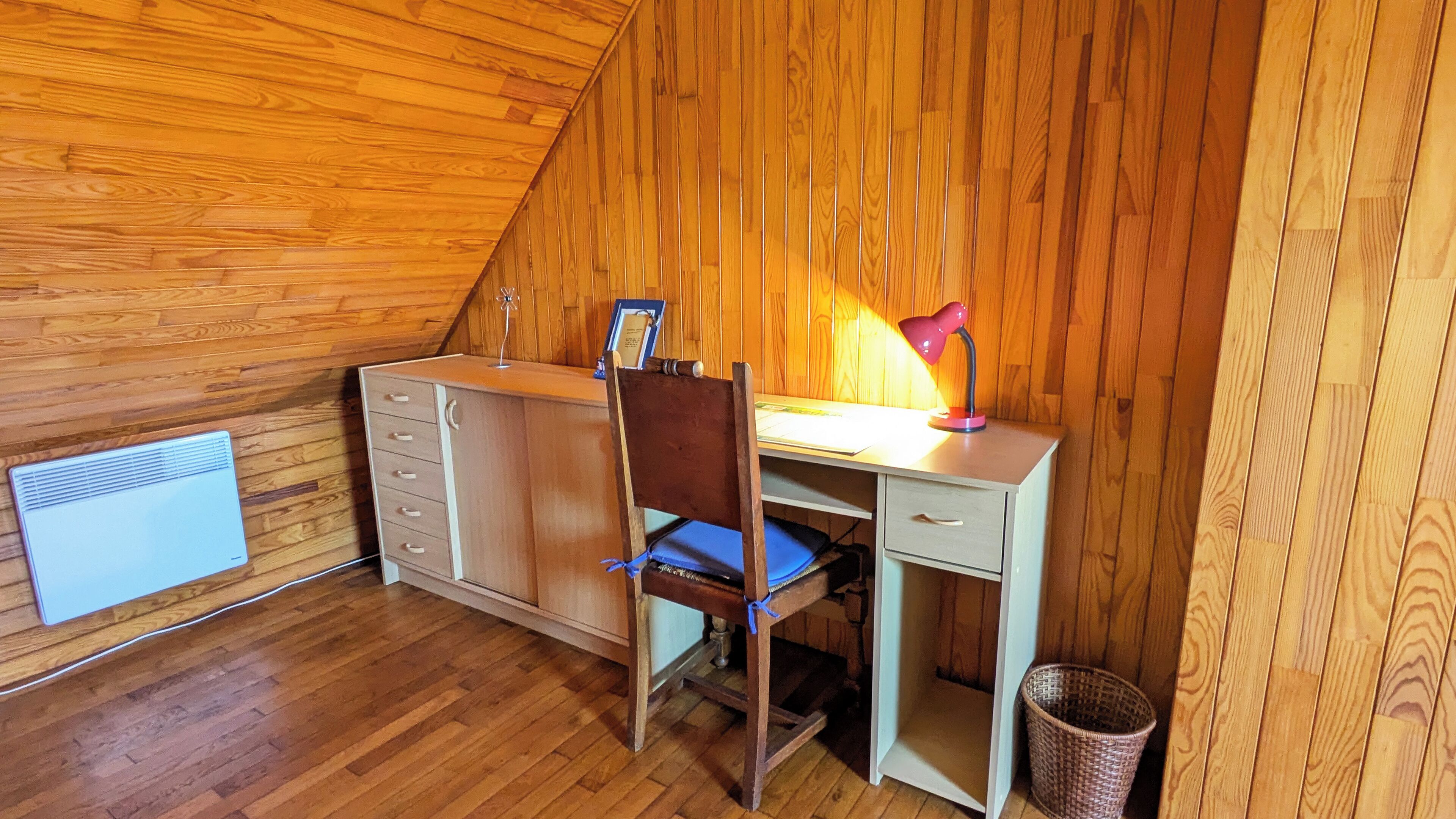 Et lille, møbelindrettet soveværelse på loftet med skrivebord, stol og radiator.