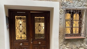 A wooden double door with decorative glass panels and a metal grille on a stone wall. - HISTORIC CITY STUDIO (Vence)