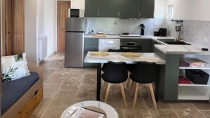 A compact kitchen with a dining area, a built-in oven, and a refrigerator. - T2 apartment for rent (Chorges)