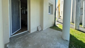 En byggnad med en uteplats i betong, en dörr som leder in till ett inre utrymme och ett litet fönster.