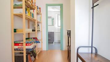 A hallway with a wooden bookshelf, a metal bench, and a green door leading to a room.