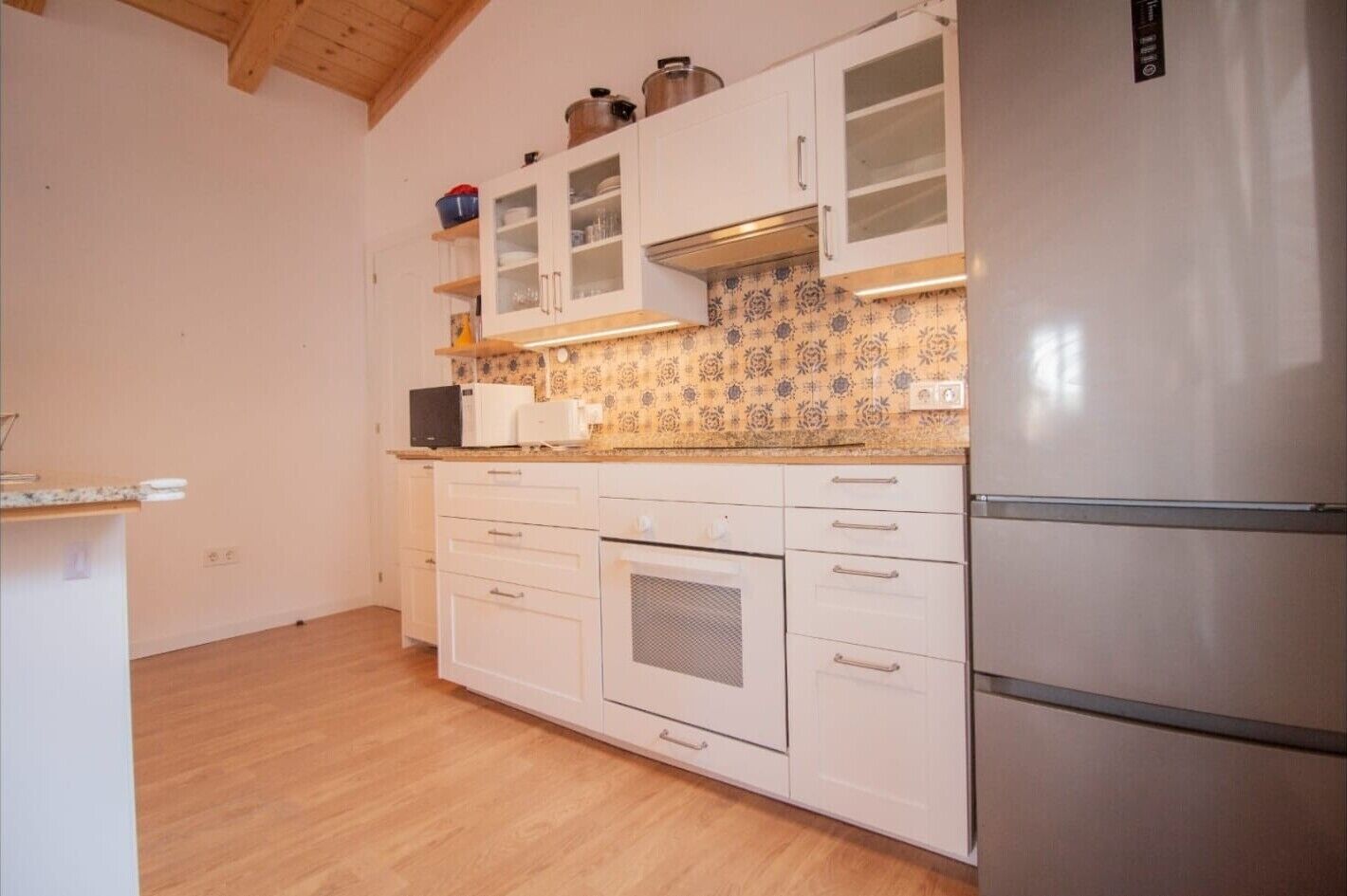 Una cocina con armarios blancos, un microondas, una estufa y un refrigerador.