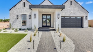 A modern two-story house with a stone facade, a central entrance with a black door, and a garage. - Upscale Oasis! Luxe Chandler Gem w/ Patio (Chandler)