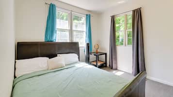 A bedroom with a bed, a bedside table, and a window with curtains.