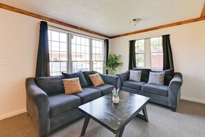 A living room with two dark gray sofas, a wooden ceiling, and large windows with curtains. - 2 Mi to Center City: Charlotte North End Home (Charlotte)