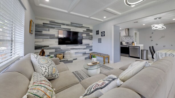 A modern living room with a large flat-screen TV, a sofa set, a coffee table, and a kitchen area in the background. - 3 Mi to Beach: Home w/ Outdoor Space in Hollywood (Hollywood)