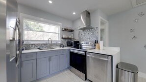 A modern kitchen with grey cabinets, stainless steel appliances, and a patterned backsplash. - 3 Mi to Beach: Home w/ Outdoor Space in Hollywood (Hollywood)