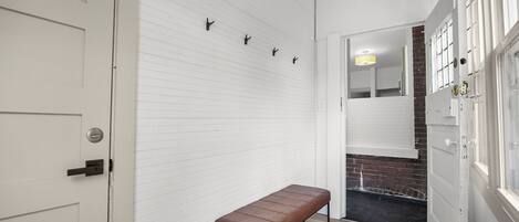 A hallway with a bench, white walls, and a door.