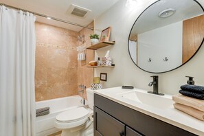 A modern bathroom with a bathtub, toilet, and sink. There are shelves with toiletries and a mirror above the sink. - < 1 Mi to Old Town: Scottsdale Condo w/ Balcony (Scottsdale)
