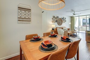 A dining area with a wooden table set for four, surrounded by chairs. A woven light fixture hangs above, and a wall-mounted tapestry is visible. - < 1 Mi to Old Town: Scottsdale Condo w/ Balcony (Scottsdale)