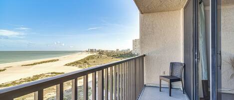 A balcony with a view of the beach and ocean.