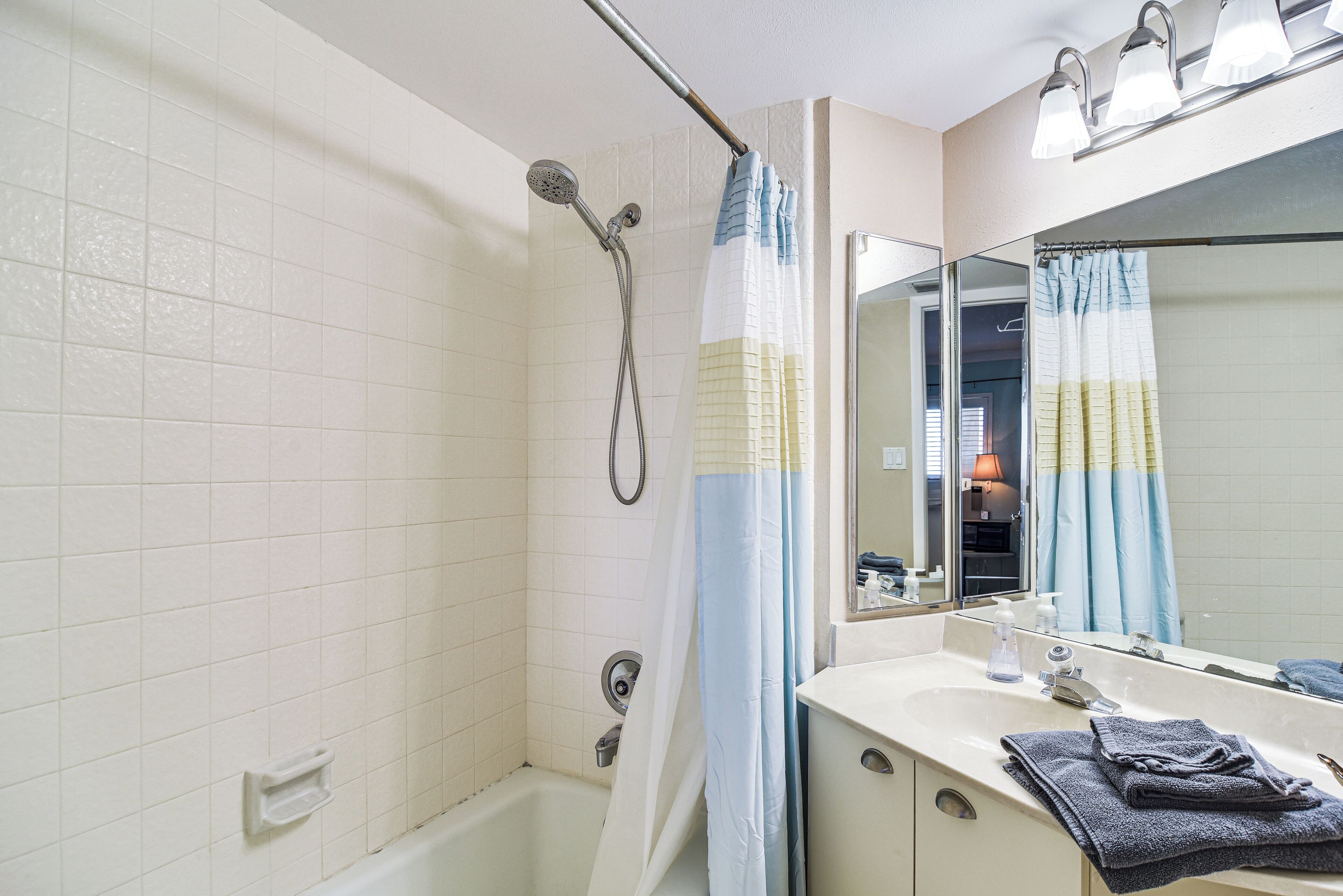 Un baño con ducha, lavamanos y espejo.