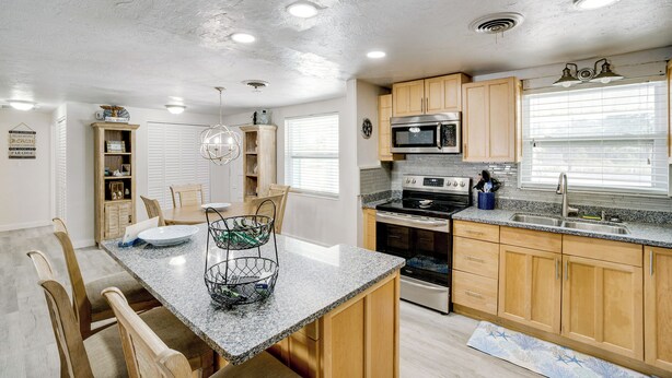 A modern kitchen with granite countertops, wooden cabinets, and stainless steel appliances. - 2 Mi to Manasota Key Beach: Home w/ Yard (Englewood)