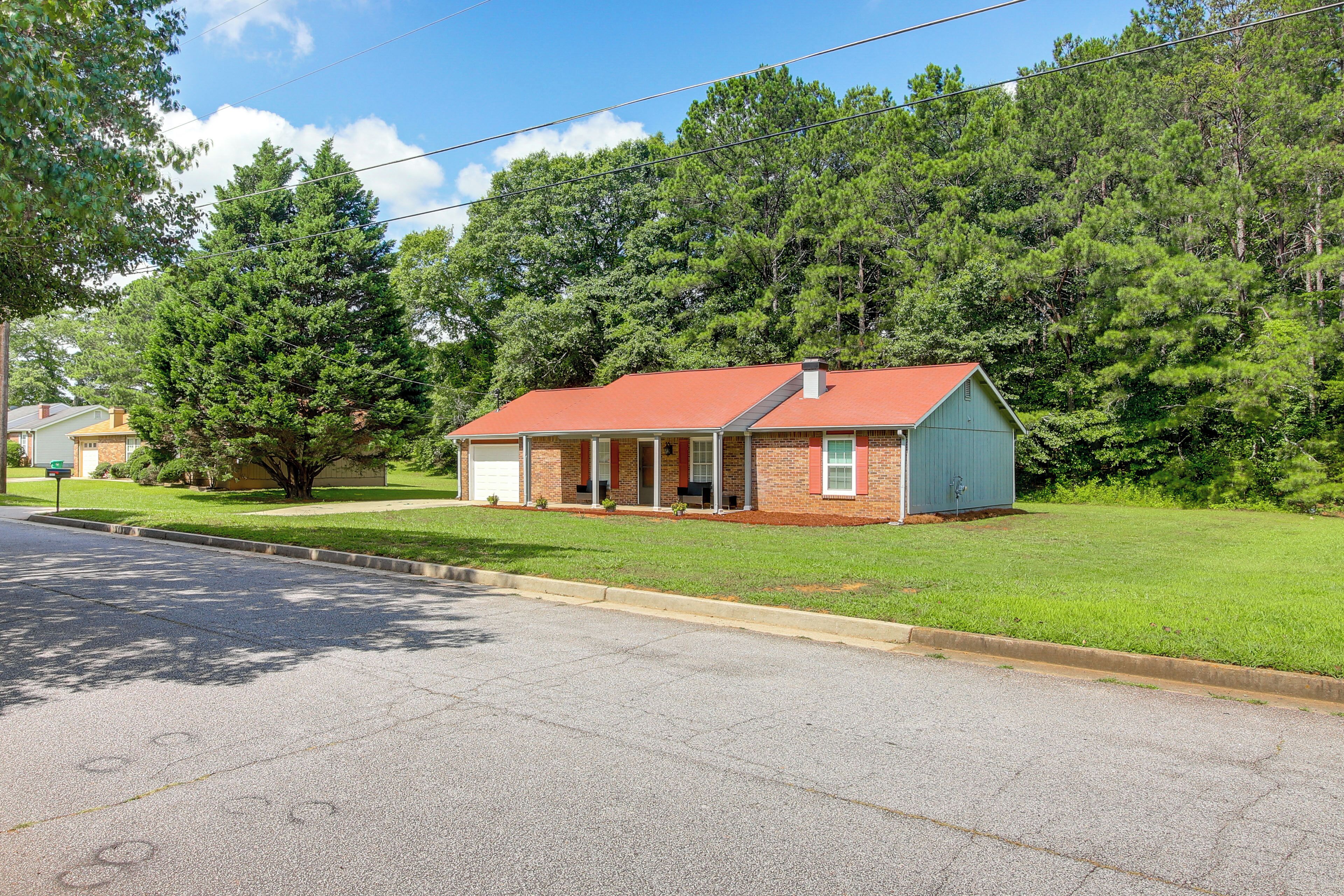 A single-story house with a red roof, a front porch, and a garage.