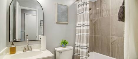 A bathroom with a toilet, sink, mirror, and shower curtain.