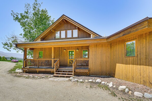 Une cabane en bois avec une véranda, une porte d’entrée et une grande fenêtre.