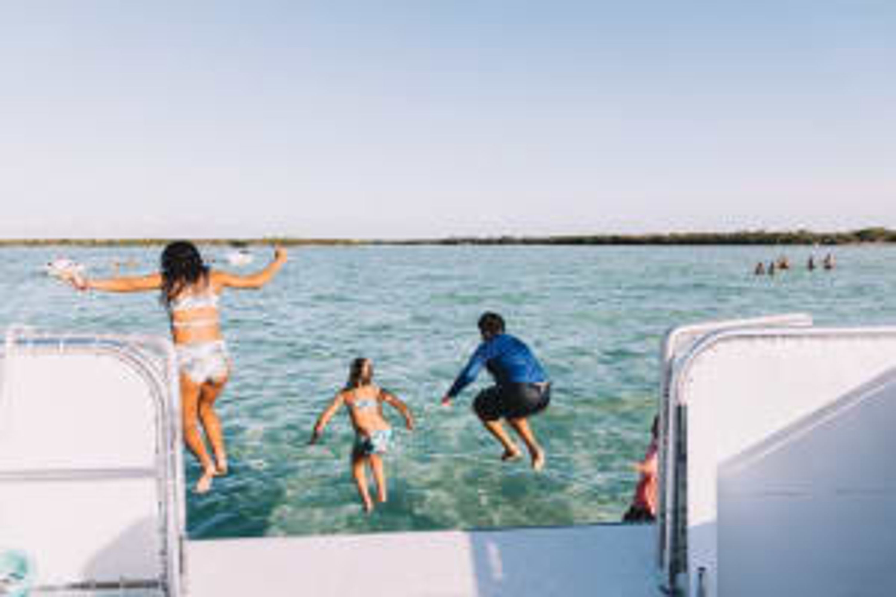 Un bote con gente saltando al agua.