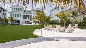 A modern resort with a well-maintained lawn, outdoor seating area, and a large building with multiple floors. - New Waterfront Home - Dreamside House (Key West)