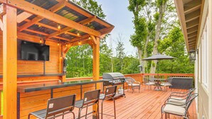 A wooden deck with a grill, bar area, and outdoor seating. - < 1 Mi to Raystown Lake: Family-friendly Cottage! (Huntingdon)
