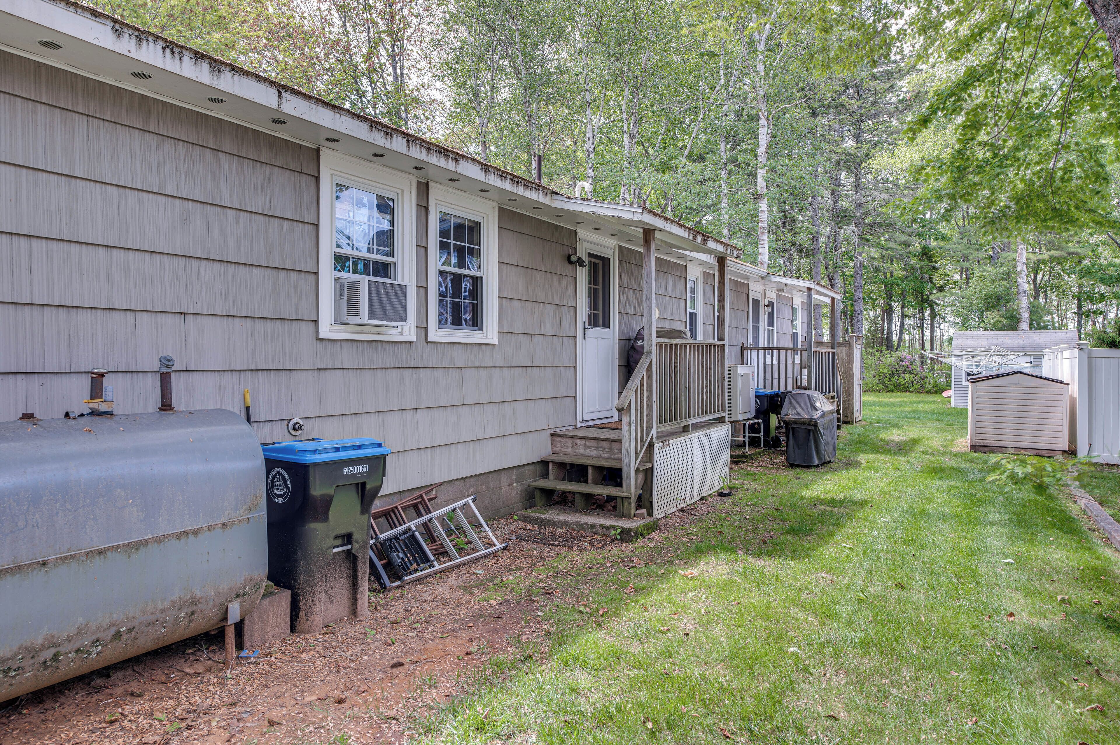 A mobile home with a porch, a water tank, and a trash bin.