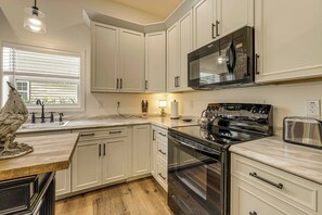 A kitchen with white cabinets, a stainless steel microwave, a stove, and a toaster.