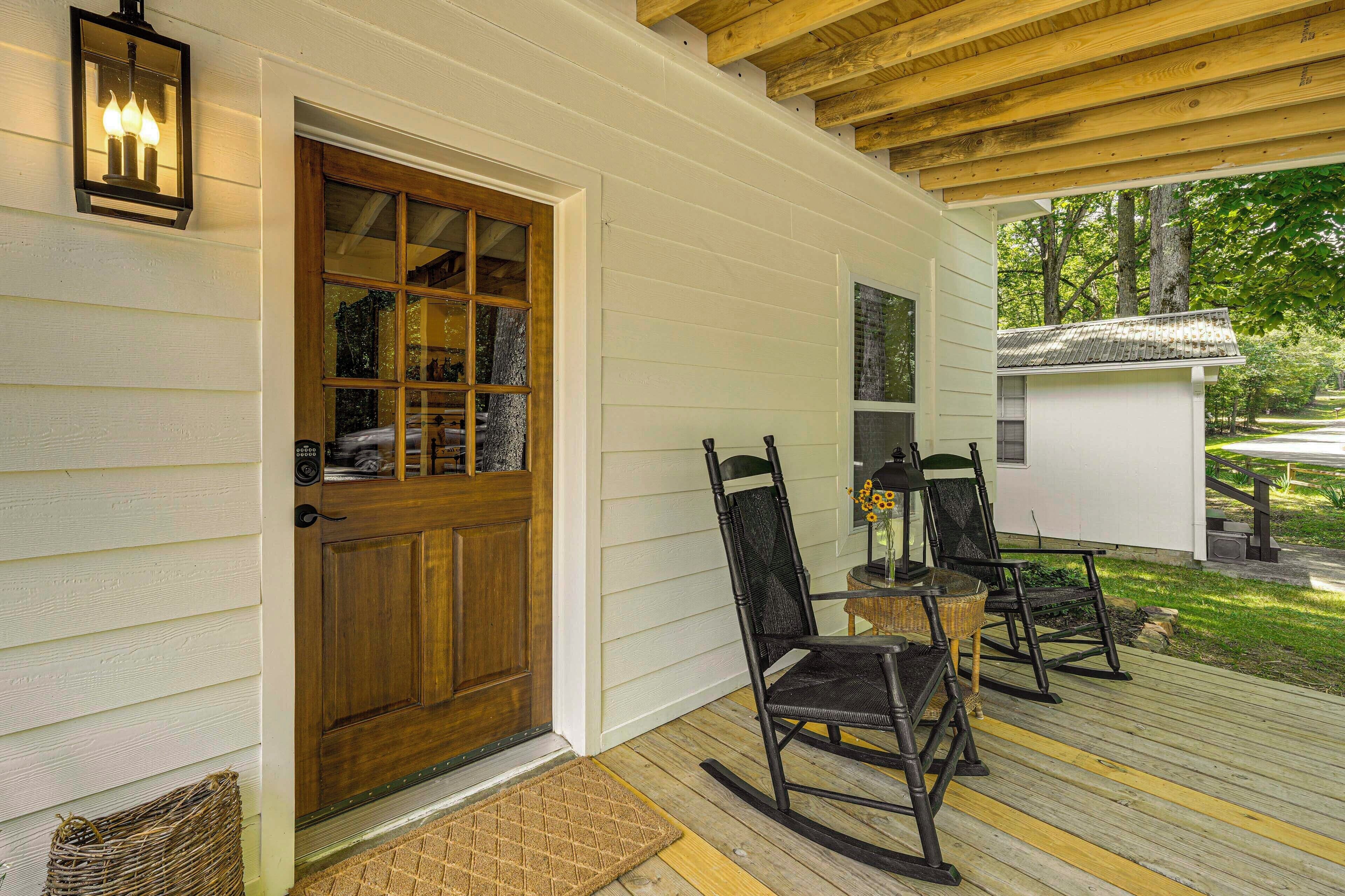 A wooden deck with rocking chairs and a white building with a wooden door.