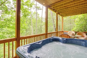 Ein Whirlpool auf einer Holzterrasse mit Blick auf einen Wald.