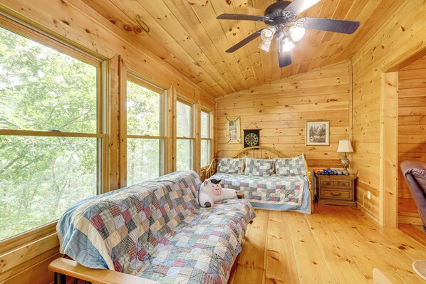 A cabin with two beds, a ceiling fan, and large windows. - Pet-friendly Resort Cabin 5 Mi to Dtwn Ellijay! (Ellijay)