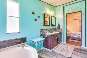 Une salle de bain avec une baignoire, deux lavabos, un meuble-lavabo et un miroir.