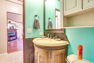 Un baño con lavabo, espejo, toalleros y un inodoro.