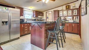 A kitchen with a central island, wooden cabinets, a stainless steel refrigerator, and a ceiling fan.