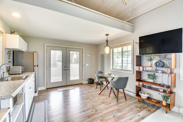 A modern kitchen with a dining area, wooden floors, and a large window. - Home w/ Lake Views on Finger Lakes Wine Trail (Penn Yan)