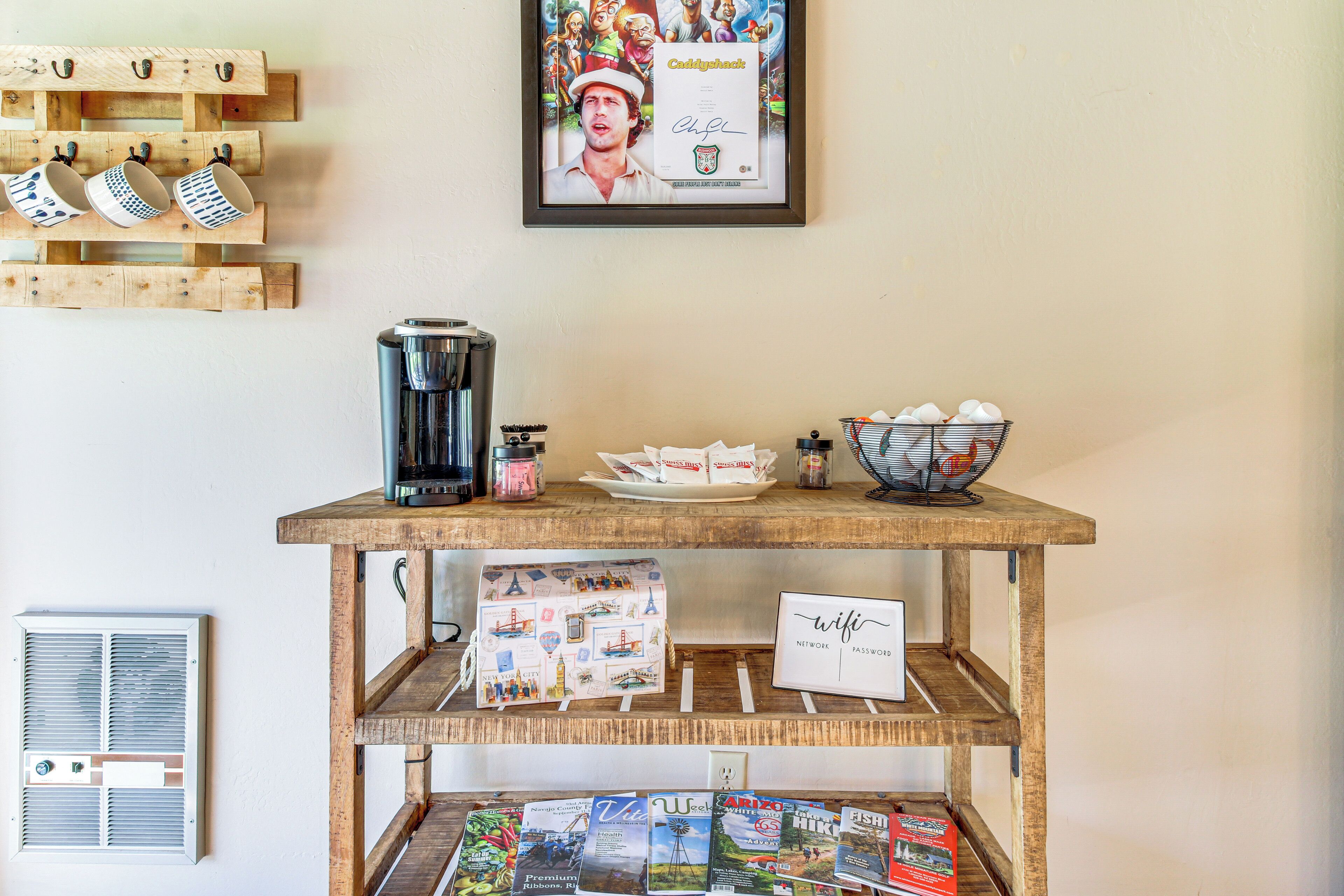 A coffee station with mugs, a coffee maker, and a bowl of snacks.