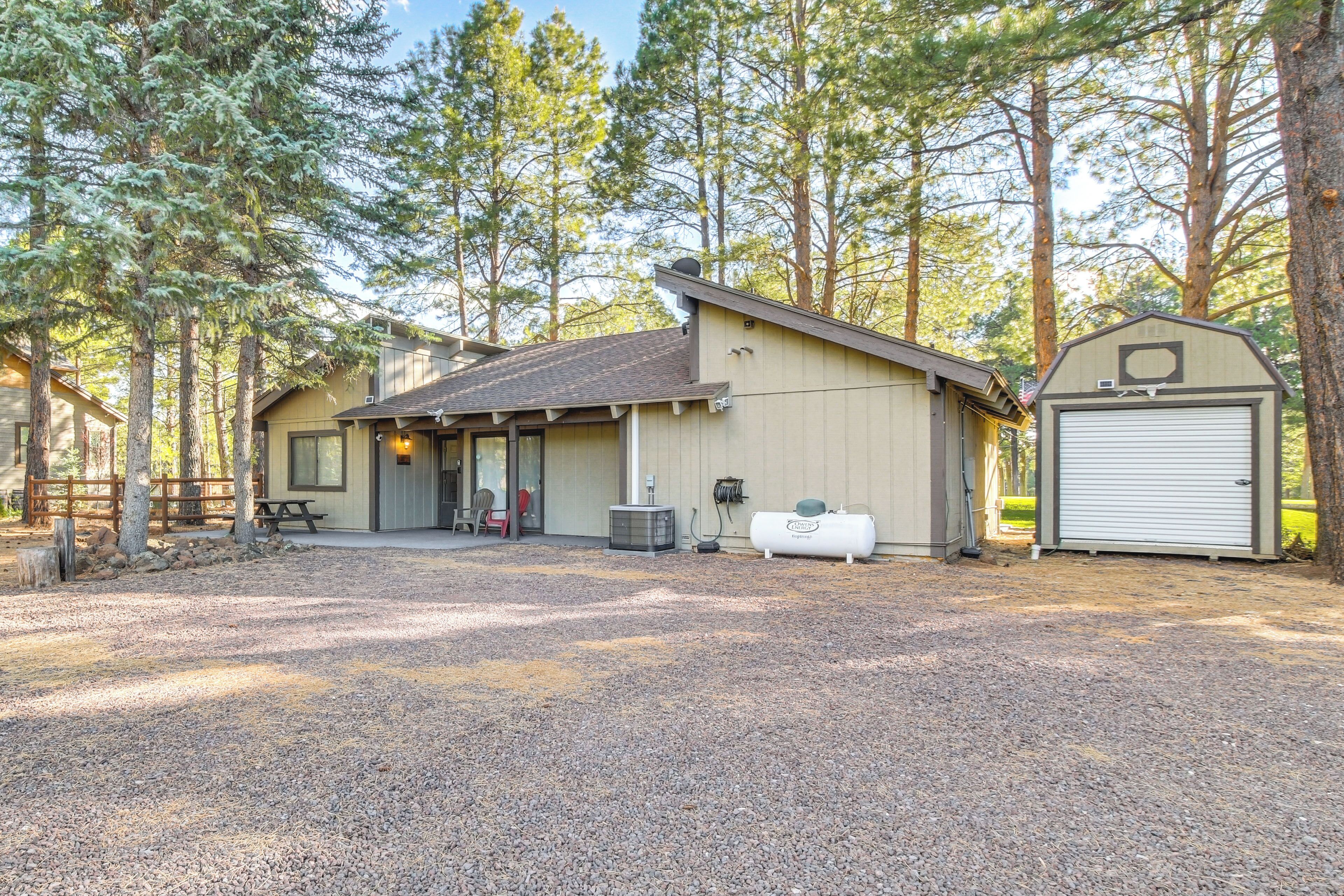 A rustic cabin with a gravel driveway, a covered picnic table, and a garage.