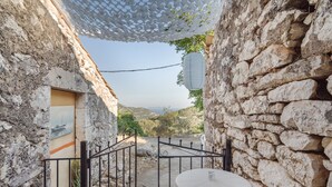 A stone-walled courtyard with a round table and chairs, a metal gate, and a hanging lantern. - Holiday Home 'Lainaki' with Sea View, Wi-Fi and Air Conditioning (Lefkada)