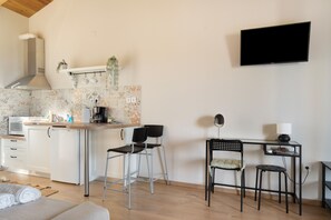 A compact living space with a kitchenette, a flat-screen TV, and a dining area with chairs and a small table.
