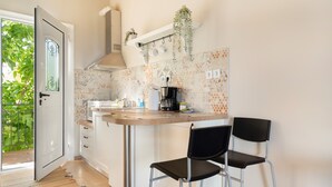Eine Küche mit Holzarbeitsplatte, zwei schwarzen Stühlen, einer hängenden Pflanze und einer Tür zum Balkon.