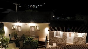 Ein zweistöckiges Haus mit Natursteinfassade, einer Holztreppe und einem Balkon mit Pflanzen.