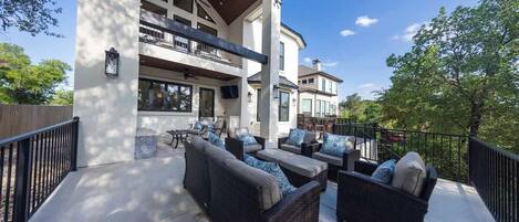 A spacious outdoor patio with wicker furniture and a view of a large house.