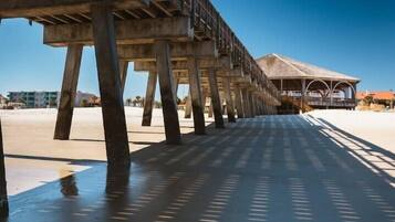 A pier extending over a beach with a covered structure at the end.