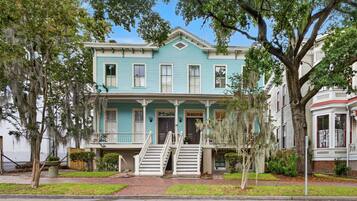 A two-story house with a front porch and a staircase leading to the entrance.