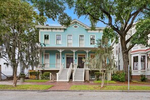 A two-story house with a front porch and a staircase leading to the entrance.
