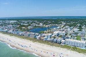 Vista aérea de uma cidade costeira com uma praia, um hotel grande e um lago.
